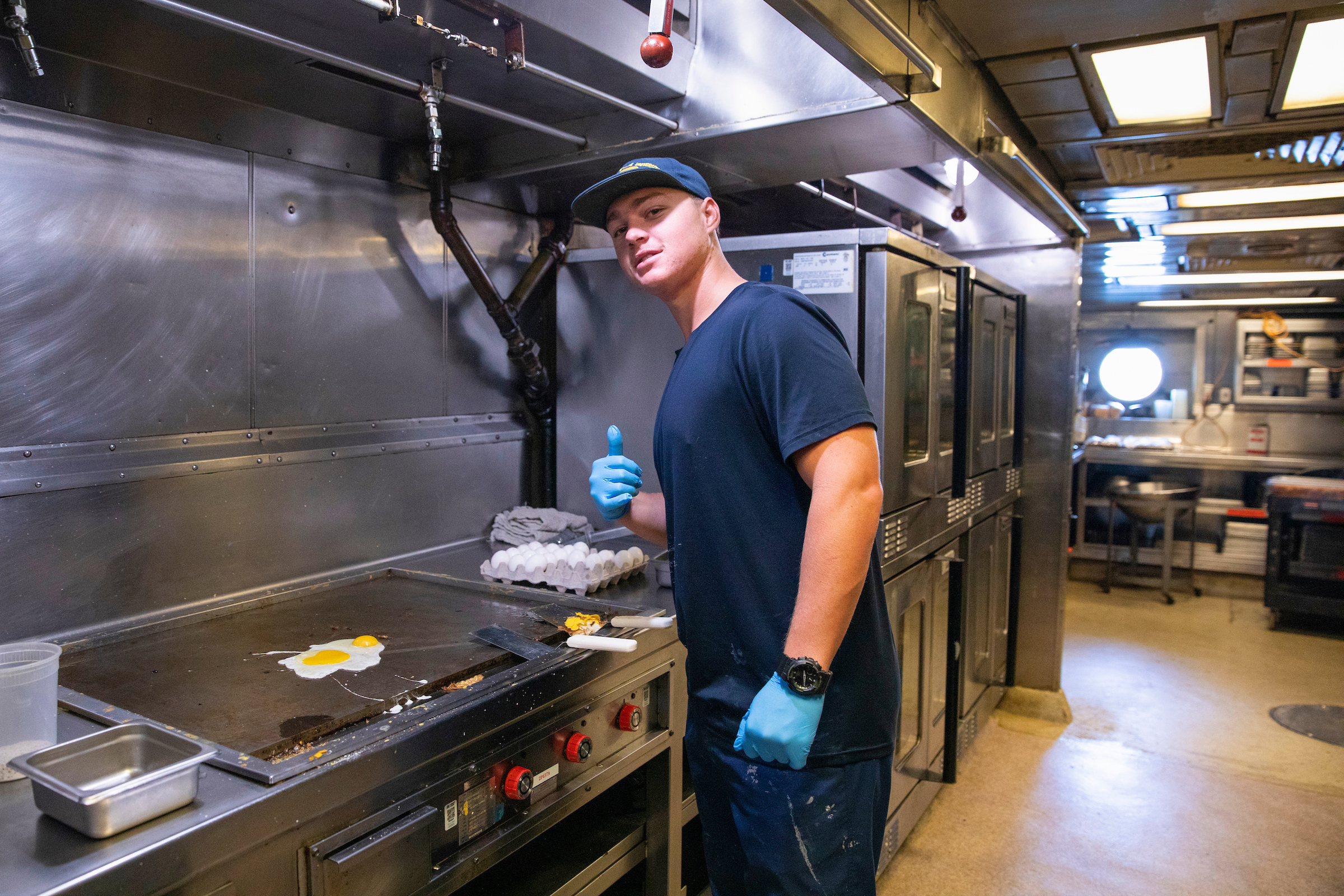 a person cooking eggs on a stove in an industrial kitchen