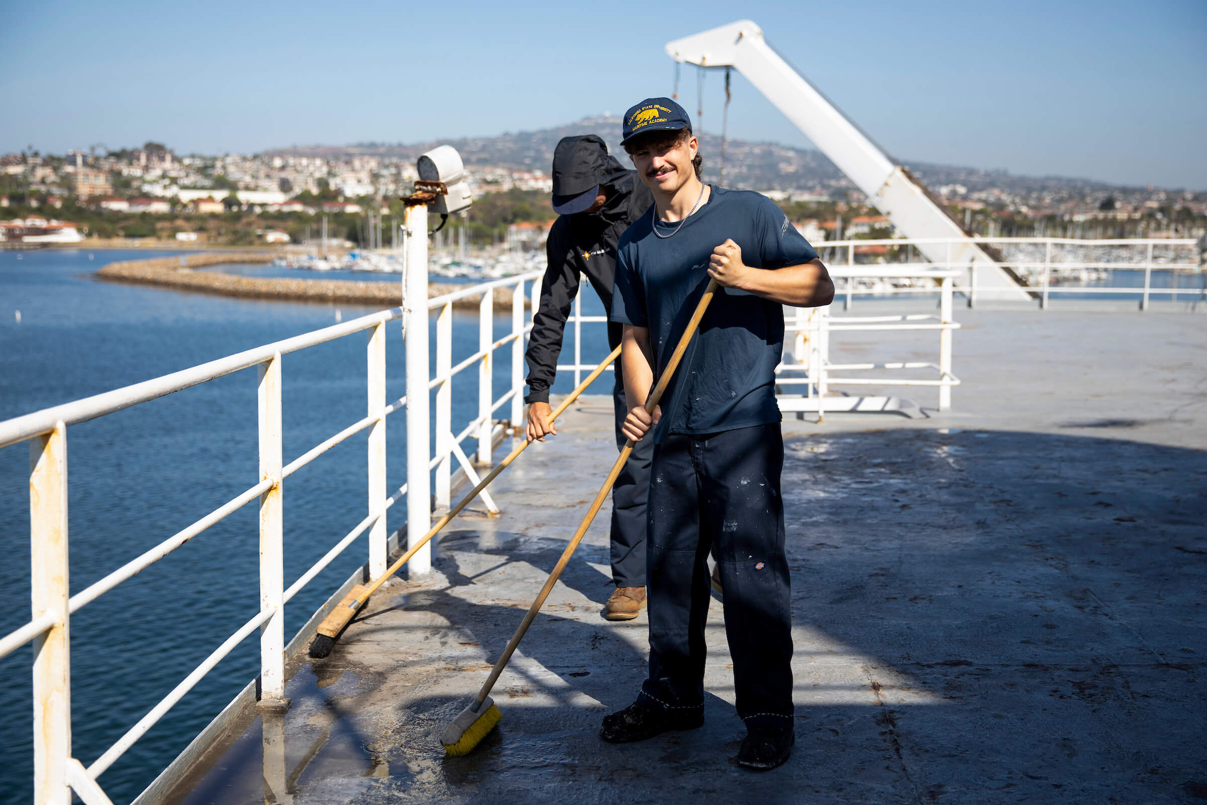 two cadets clean the ship deck.