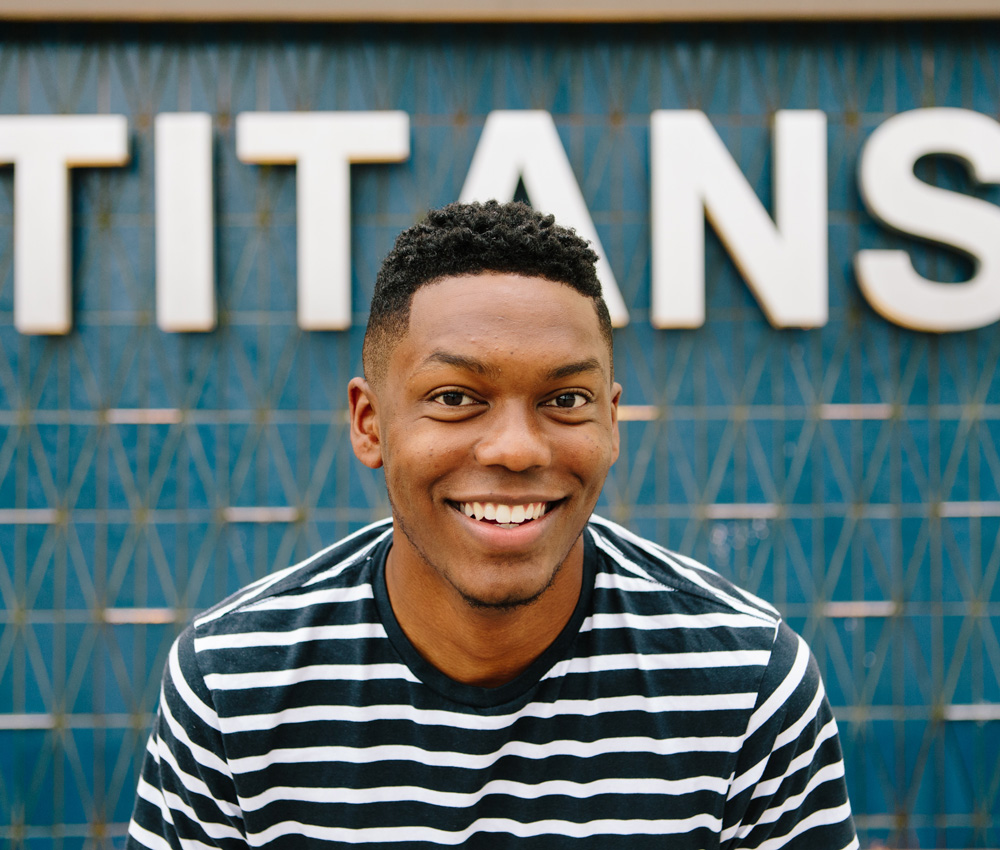 Josh stands in front of a Titan sign. 