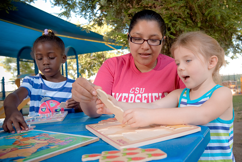 teacher with young children building a puzzle