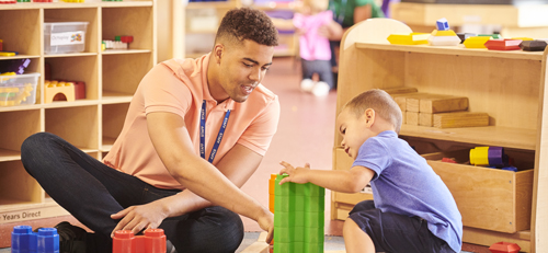 teacher building blocks with young child
