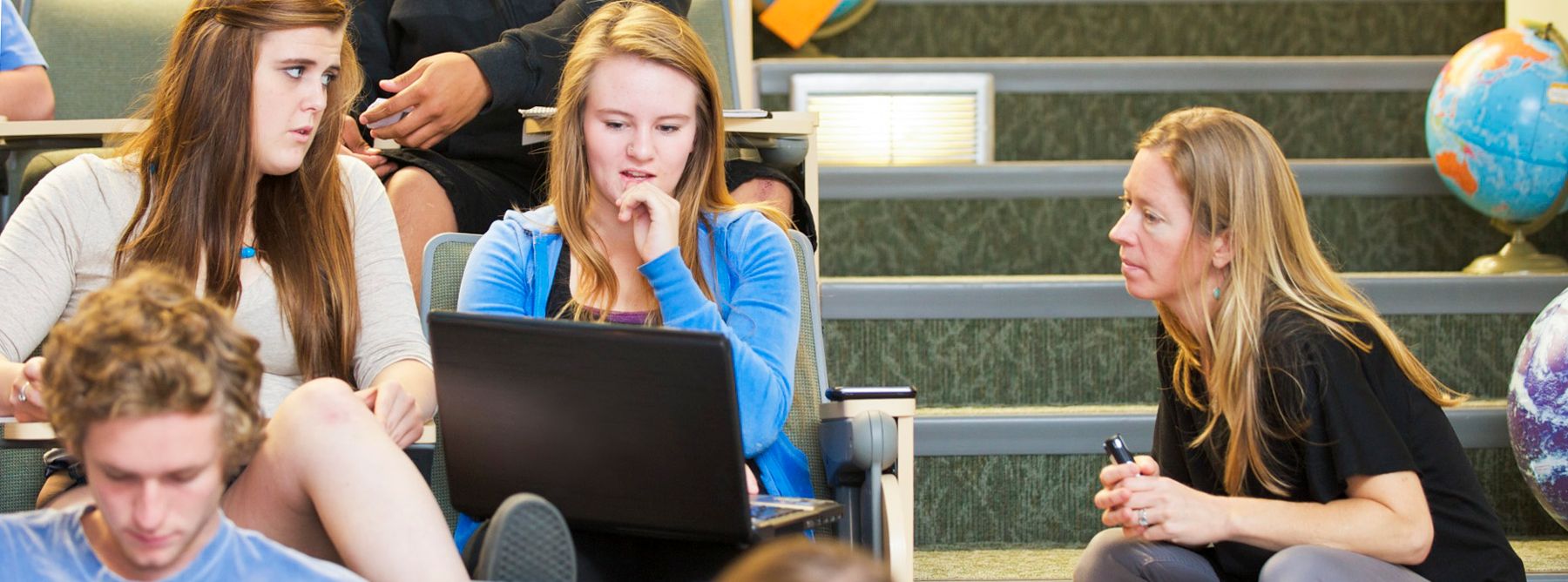 student on her laptop getting help from a professor